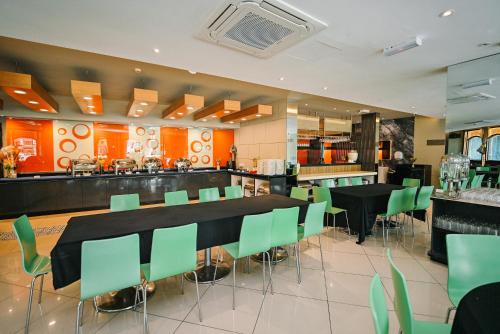 a restaurant with black tables and green chairs at Kingston Hotel 11 - PWTC, KL in Kuala Lumpur
