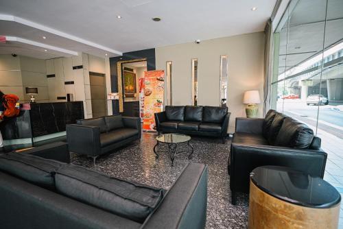 a living room with black leather couches and a table at Kingston Hotel 11 - PWTC, KL in Kuala Lumpur
