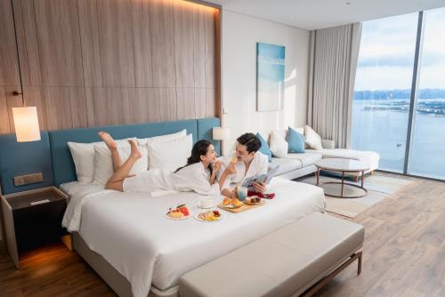 two women laying on a bed in a hotel room at A La Carte Ha Long Bay Managed by TASECO in Ha Long