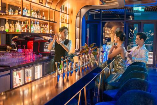a group of people standing at a bar at A La Carte Ha Long Bay Managed by TASECO in Ha Long