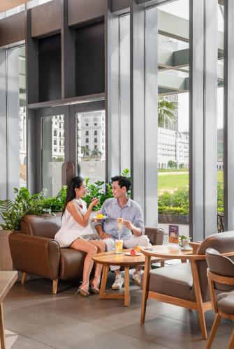 a man and woman sitting on a couch in a lobby at A La Carte Ha Long Bay Managed by TASECO in Ha Long