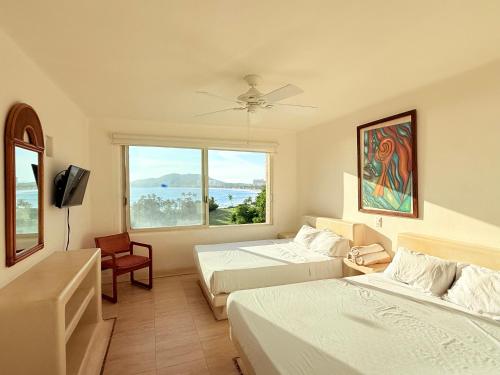 a hotel room with two beds and a large window at Departamentos Frente al Mar en Ixtapa in Ixtapa