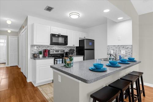 a kitchen with white cabinets and a counter with blue dishes on it at Luxury 3BR Condo Near Disney with Pool in Kissimmee