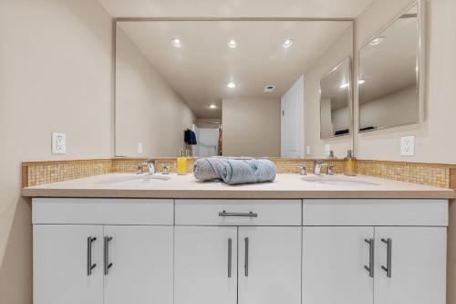 Un baño con dos lavabos y un espejo grande. en Azure Marina Luxe - Waterfront with Sunset Views, en Los Ángeles