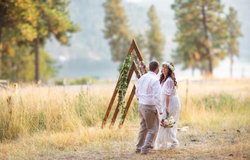 a bride and groom standing in front of an arch at Cabin Getaway with Lake View! in Coeur d'Alene