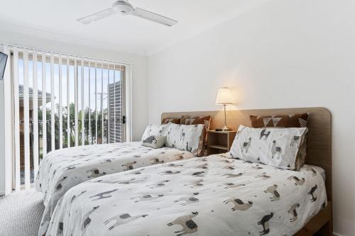a white bedroom with two beds and a window at 1-68 Woodburn Street in Evans Head