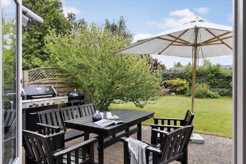 a table and chairs with an umbrella and a grill at FJ1200-Jaegerspris-Planetvej-8 in Jægerspris