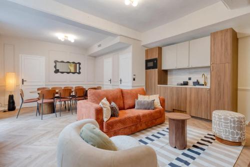 Splendid 10PAX apartment in the center of Paris في باريس: غرفة معيشة مع أريكة برتقالية وطاولة