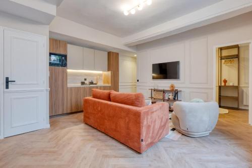 Splendid 10PAX apartment in the center of Paris في باريس: غرفة معيشة مع أريكة برتقالية وكرسي أبيض