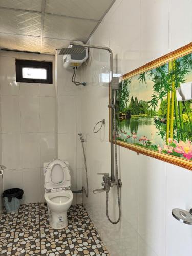 a bathroom with a toilet and a painting on the wall at Horizon Homestay in Phong Nha