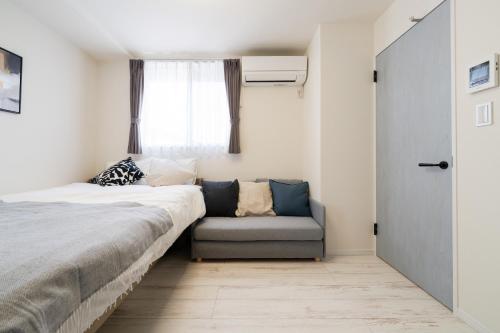 a bedroom with a bed and a couch and a window at Intervia Horikiri in Tokyo