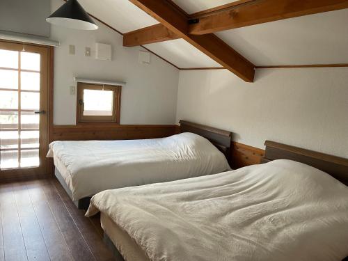 a bedroom with two beds and a window at A private inn where you can relax in nature and enjoy with groups of up to 14 people in Kaminoyama