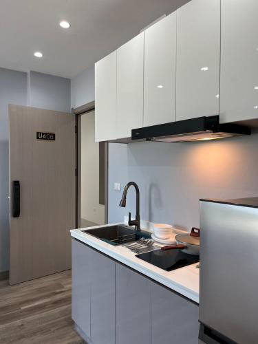 a kitchen with white cabinets and a sink at UPMOON Hotel in Ban Suan