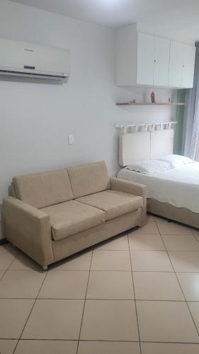 a couch sitting next to a bed in a room at Prainha Arraial do Cabo Loft in Arraial do Cabo