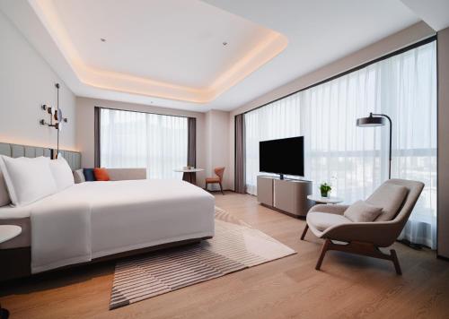 a bedroom with a large white bed and a chair at Novotel Xiamen Downtown in Xiamen