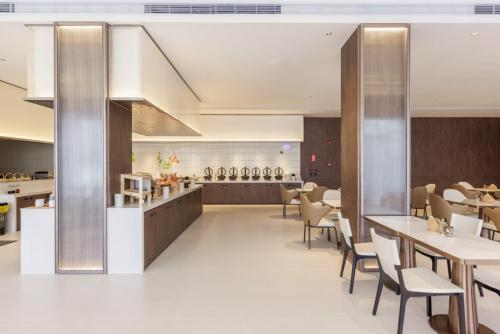 a restaurant with tables and chairs and a counter at Atour X Hotel Guangzhou Baiyun International Airport Renhe Station in Guangzhou