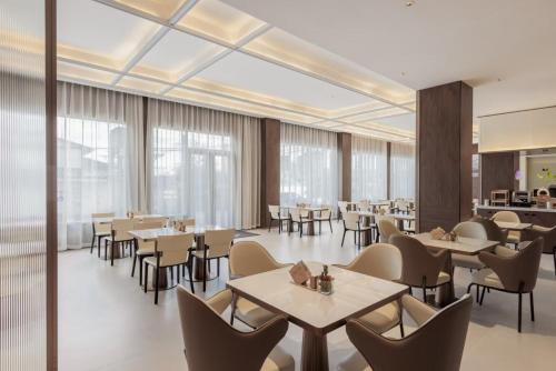 a restaurant with tables and chairs and windows at Atour X Hotel Guangzhou Baiyun International Airport Renhe Station in Guangzhou