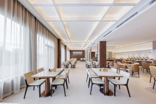 a dining room with tables and chairs and windows at Atour X Hotel Guangzhou Baiyun International Airport Renhe Station in Guangzhou