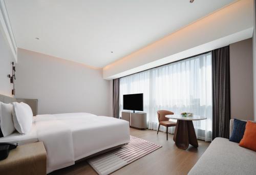 a bedroom with a large white bed and a table at Novotel Xiamen Downtown in Xiamen