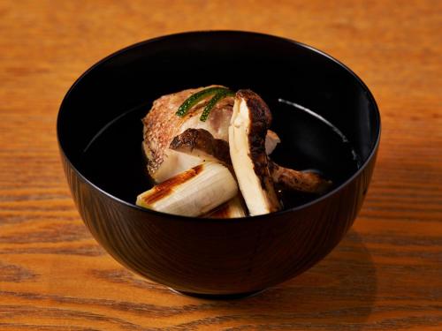 a black bowl filled with food on a wooden table at Hakone Hisui in Hakone