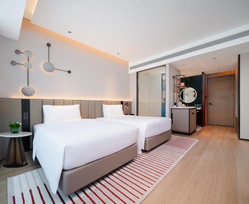 a bedroom with two white beds and a rug at Novotel Xiamen Downtown in Xiamen