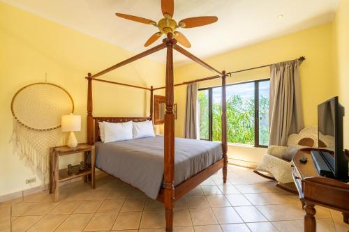 a bedroom with a canopy bed with a fan at Sunrise 7 - 2 Bedroom, Ocean View Condo in Tamarindo