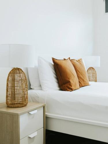 a white bed with brown pillows and a table at Life in Byron Hostel in Byron Bay