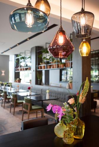 a table with vases and flowers on it in a restaurant at Van der Valk Hotel Nijmegen-Lent in Nijmegen
