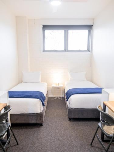 two beds in a room with a window at Life in Byron Hostel in Byron Bay