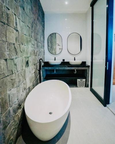 a large white tub in a bathroom with two sinks at Villa Matahari Ubud in Gianyar