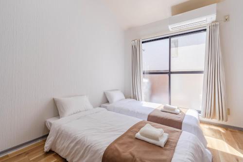 two beds in a room with a window at Wajiro Good Place House in Fukuoka