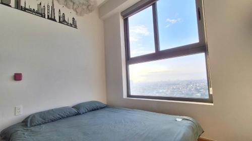 a bed in a room with a large window at Bcons Garden Luxury Aparment in Dĩ An