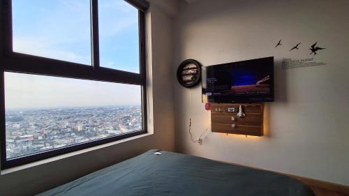 a room with a tv and a bed and a window at Bcons Garden Luxury Aparment in Dĩ An