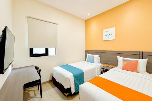 a hotel room with two beds and a flat screen tv at SANS Siliwangi Semarang in Kalibanteng-kidul