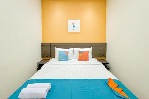 a bedroom with a large bed with colorful pillows at SANS Siliwangi Semarang in Kalibanteng-kidul
