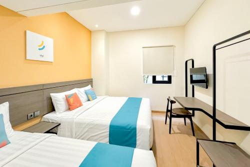 a hotel room with two beds and a desk at SANS Siliwangi Semarang in Kalibanteng-kidul