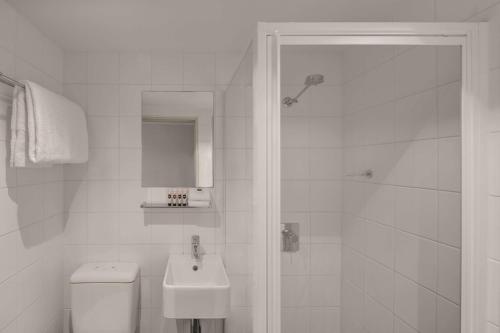 a white bathroom with a toilet and a sink at Travelodge Hotel Hobart in Hobart
