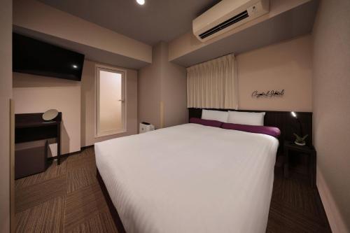 a bedroom with a large white bed and a window at Nipponbashi Crystal Hotel in Osaka