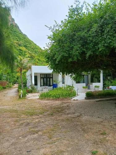 a small white house in front of a mountain at Brassiere Beach Hotel in Baanphakrimlay 