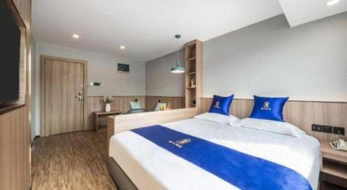a bedroom with a large bed with blue pillows at Super 8 Hotel Xiamen Railway Station in Xiamen