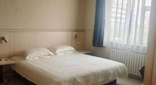a bedroom with a white bed and a window at Magnotel Business Jining Huancheng North Road in Jining