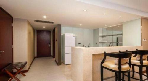a kitchen with two chairs and a counter with a refrigerator at Wuhan Soluxe Hotel in Wuhan