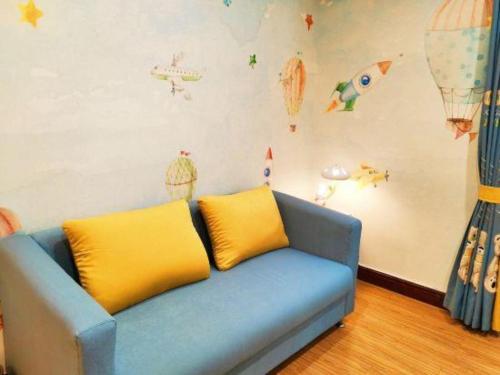 a blue couch with two yellow pillows in a room at Catic Hotel--Adjacent Buliding in Zhuhai