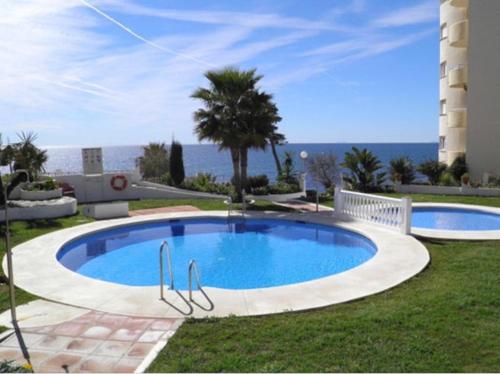 a swimming pool in a yard with the ocean in the background at Apartamento Playa Algaida in Sitio de Calahonda