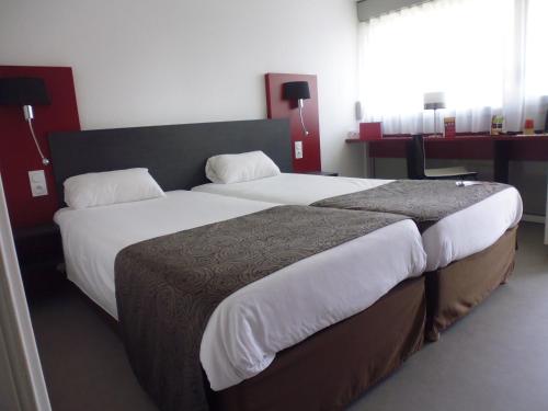 a bedroom with a large bed with white sheets at Brit Hotel Mayenne in Mayenne