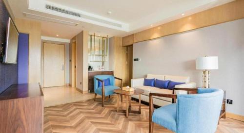 a living room with a couch and blue chairs at James Joyce Coffetel Chengdu Jichang Road Shenxianshu in Chengdu