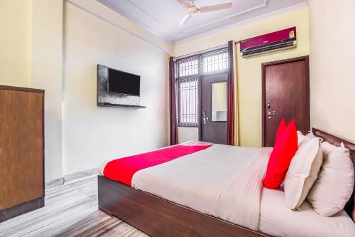 a bedroom with a bed with red pillows and a tv at Hotel O Raghukul in Jaipur
