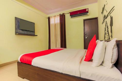a bedroom with a bed with red and white pillows at Hotel O Raghukul in Jaipur