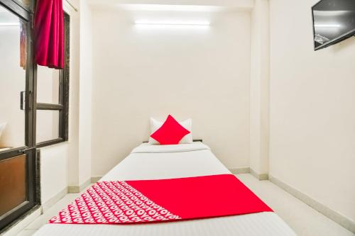 Una cama en una habitación con una almohada roja. en Hotel O Q7, en Kota