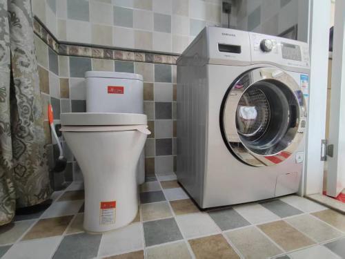 a toilet and a washing machine in a bathroom at Central Street River View Apartment in Harbin